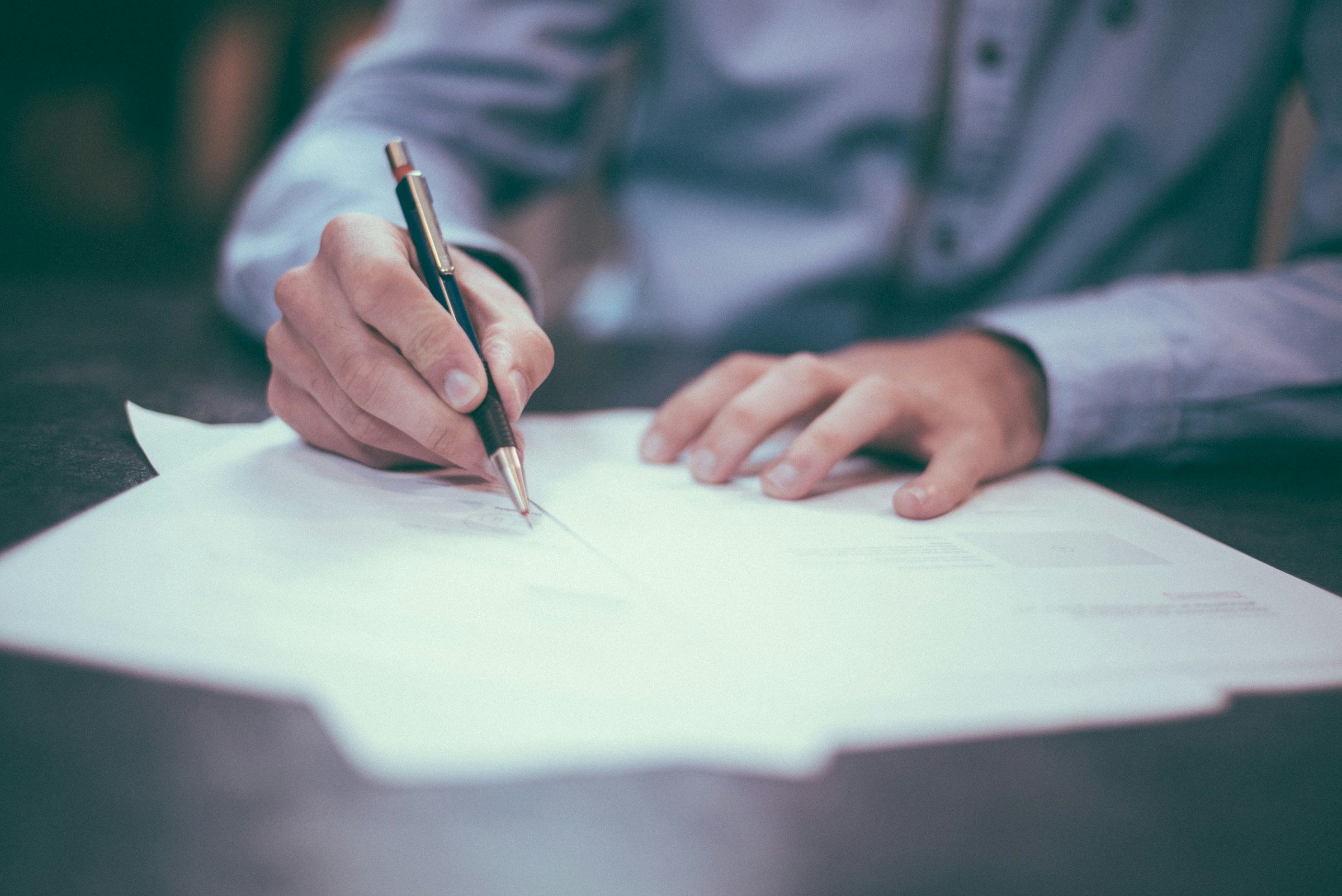 Professional carefully reviewing and signing documents at a desk