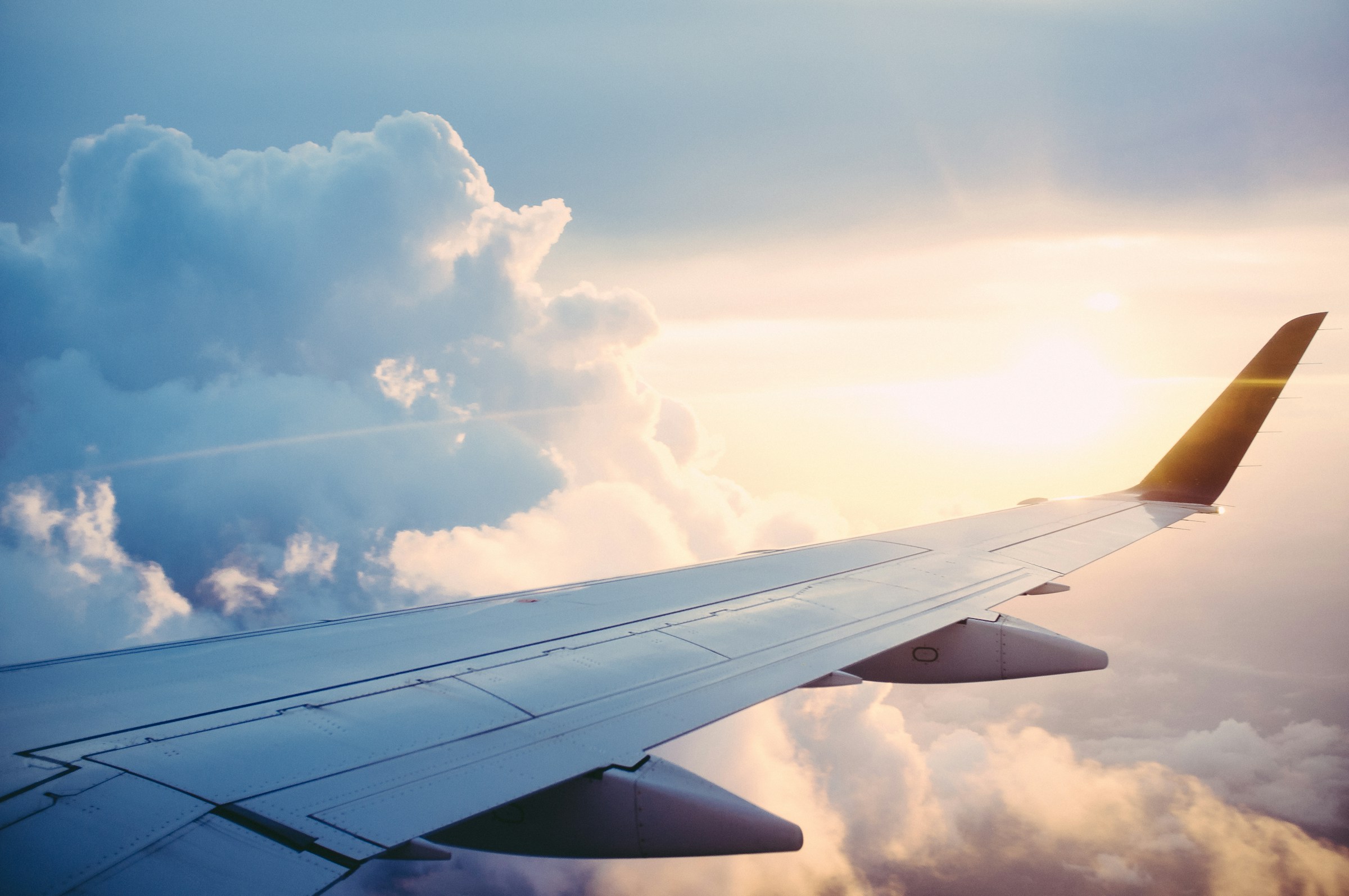 Aircraft wing over sunlit clouds